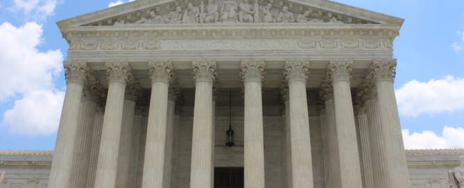 The front view of the U.S. Supreme Court building with its iconic columns and detailed pediment on a sunny day.