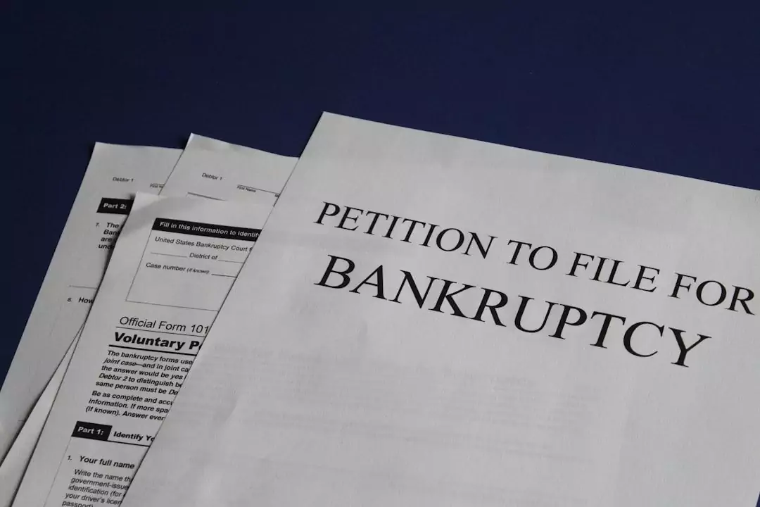A stack of documents on a dark blue surface, with the top document titled "Petition to File for Bankruptcy.