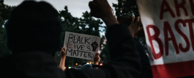 Protesters hold signs that read "Black Lives Matter" and "All Cops Are Bastards" during a demonstration.