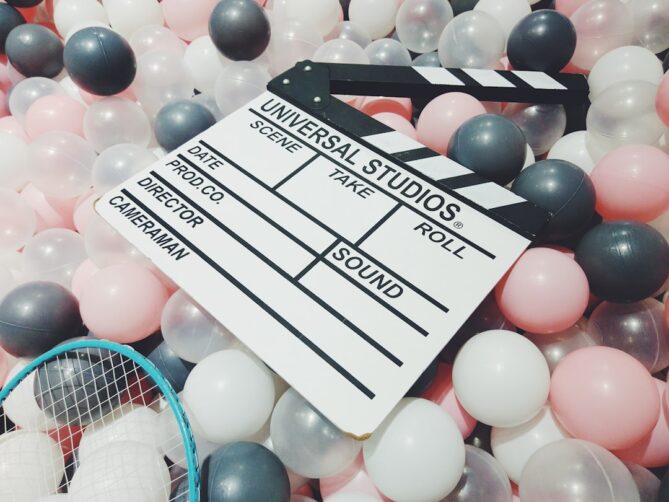 A clapperboard with "Universal Studios" written on it is placed among a mix of grey, white, and pink plastic balls.