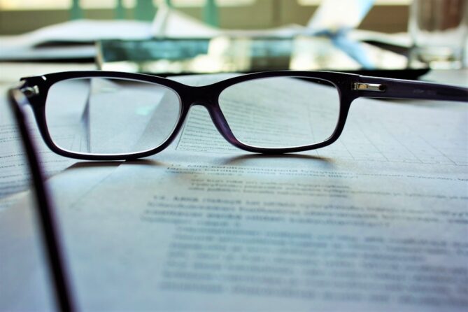 Black-rimmed eyeglasses resting on documents with text.